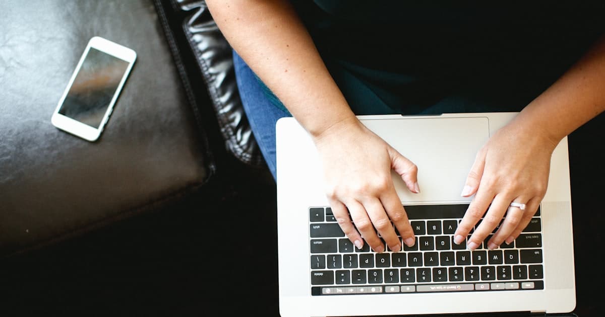person using MacBook while sitting on chair, reviewing finances